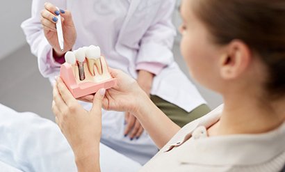 a patient holding a model of dental implants 