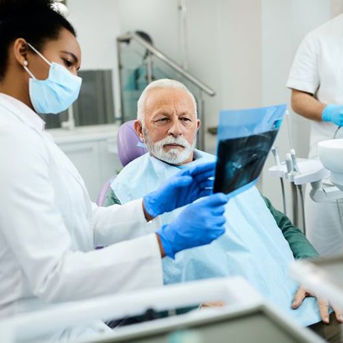 Senior patient and dental team member reviewing x-ray